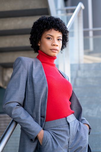 A young African-American businesswoman wearing a red turtleneck and a suit in a business building