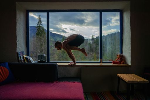 A Caucasian man doing yoga on a windowsill