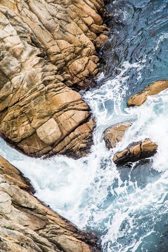 An aerial shot of sea waves hitting the rocks
