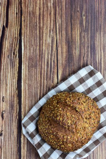 A vertical top view of rye bread on a checkered tower over a rustic wooden background with copy space