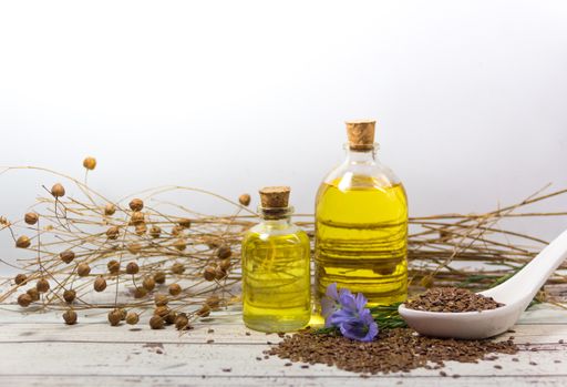 Seed flowers and flax oil bottles on white wood