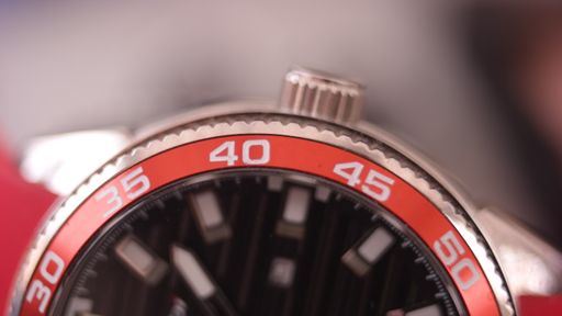 A closeup of the crown and numbers of the watch under the lights against a blurry background