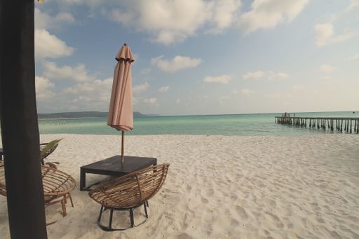 Empty wicker chairs beach umbrella facing the serene ocean on the island of Koh Rong Sanloem, Sihanoukville, Cambodia