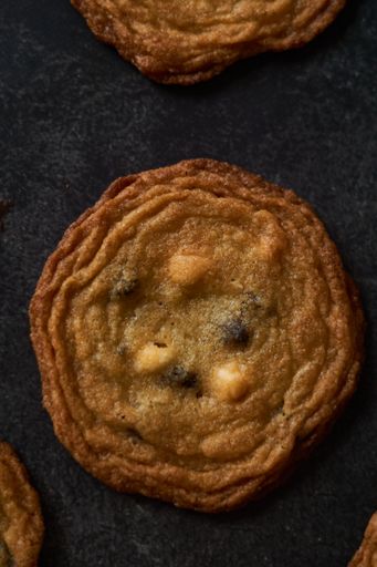 A vertical closeup shot of chocolate chips cookies on a black paper background