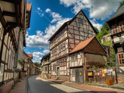 Charming medieval street with half-timbered houses under a bright blue sky in Quedlinburg, Germany.
