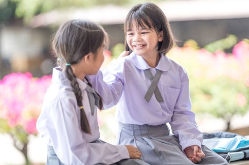 A shallow focus of two adorable kids in the school uniform playing outdoors on a sunny day