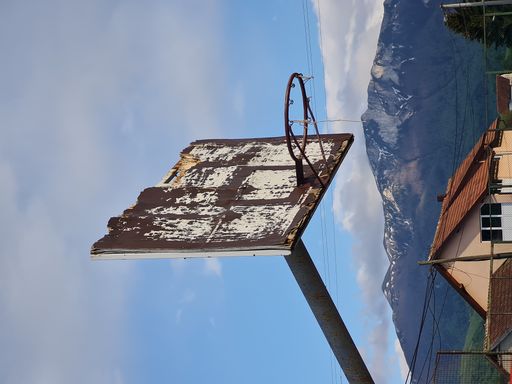 An old and rustic basketball hoop  in a village against a mountain background