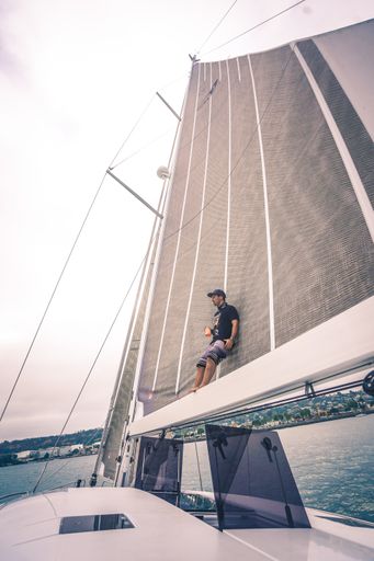 A vertical shot of a male standing on a ship and admiring the beautiful view of the sea during daytime