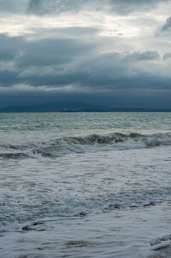 A vertical shot of a seascape under the cloudy skies during the day