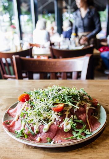 A vertical shot of raw meat with tomato and vegetables with a blurred background