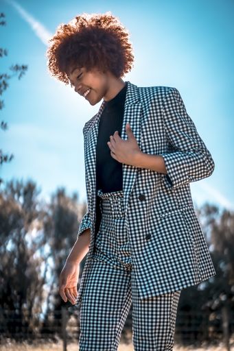 A low angle shot of a joyful female with afro hair in a formal outfit under the bright sky in a park in Spain