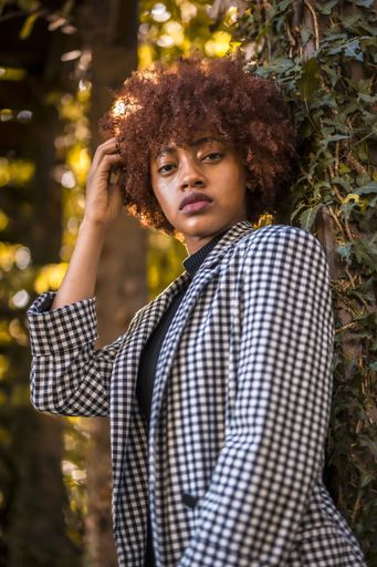 A young confident female with afro hair in a formal outfit standing in a park in Spain on a sunny day