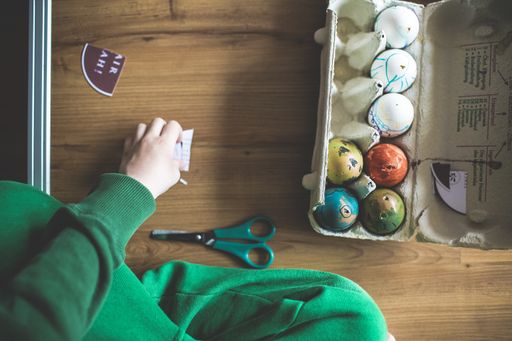 An overhead shot of an egg carton filled up with ornate eggshells, later to be used as Easter decorations