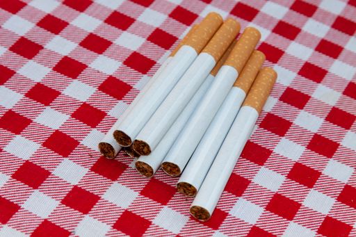 A closeup shot of a pile of cigarettes on a red and white checkered tablecloth