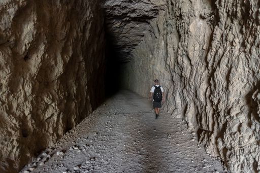 A lighted and empty tunnel with dirt and gravel floors