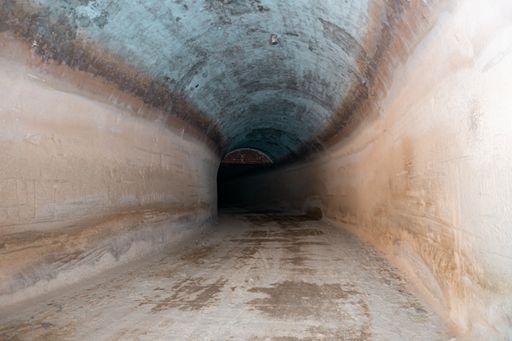 A lighted and empty tunnel with dirt and gravel floors
