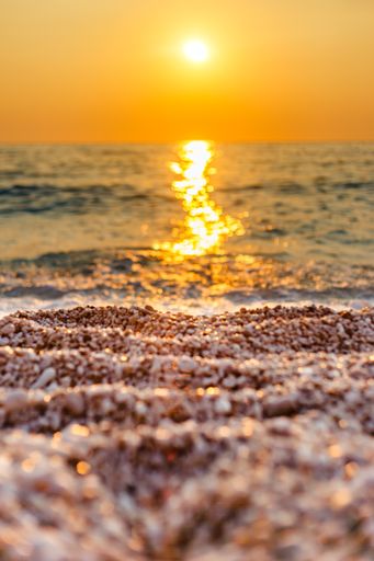 A gorgeous vertical shot of a golden sunset at Lefkada, Greece with the sun glow brightly in the orange sky