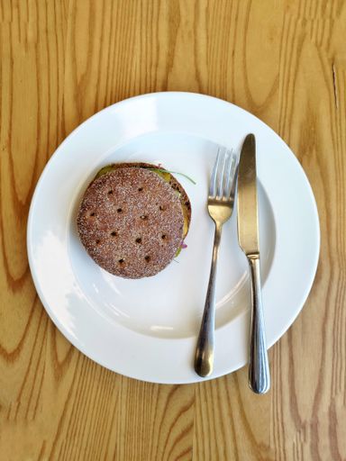 A top view of a delicious sandwich with pickles, cheese, and red onions on a ceramic plate at a cafe