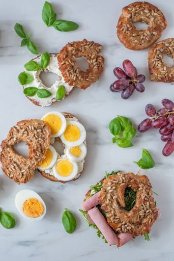 A top view of freshly baked whole grain bagels with eggs and sausages
