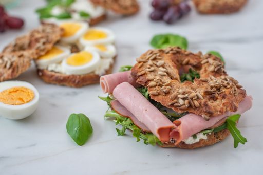 A shot of freshly baked whole grain bagels with eggs and sausage on a white surface