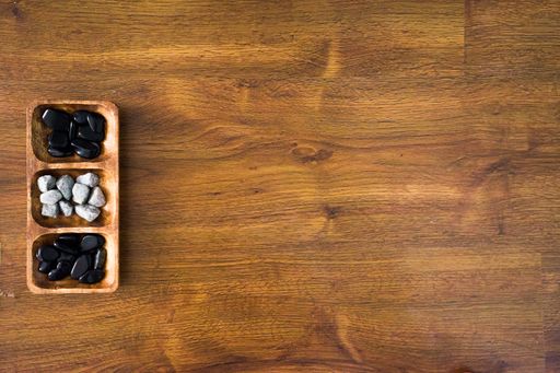 A high angle shot of white and black rocks in a wooden plate on a wooden surface