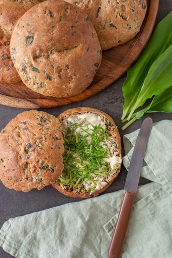 A top view of whole grain bread rolls with wild garlic