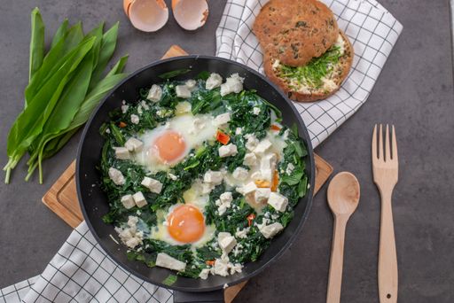 A top view of green shakshuka. Fried eggs with wild garlic and feta cheese