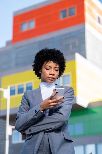 A vertical shot of a cool young African American lady dressed professionally using her phone