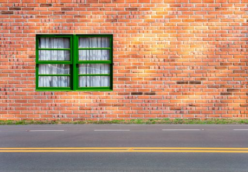 A building with brick wall and a green windowd near the street