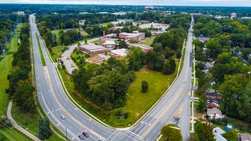 The aerial shot of the highway divided into 2 branches in the middle of green downtown.