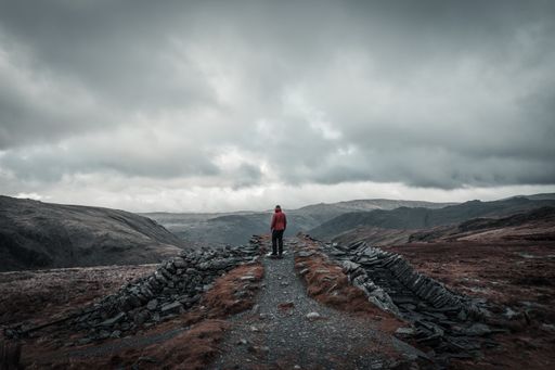 A man standing on the peak of a mountain gazing at the view on a gloomy day