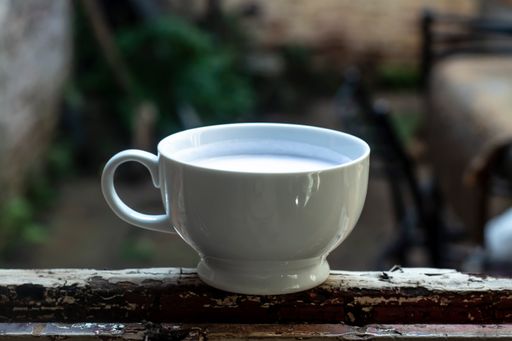 A selective focus shot of a white cup of milk outdoors