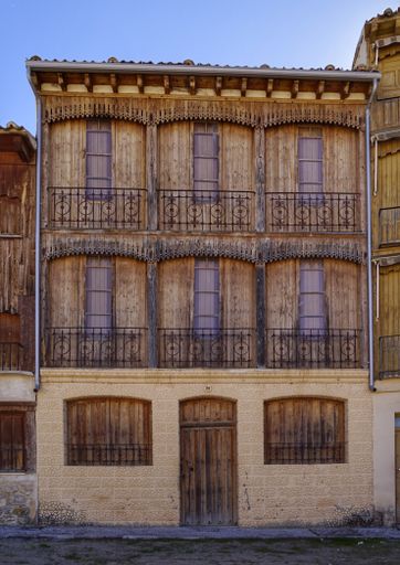 A vertical shot of an old building with wooden windows and doors