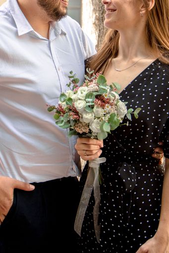The vertical shot of a beautiful happy married  couple with a rose bouquet in a woman's hand