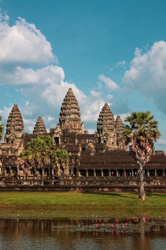 A vertical shot of ancient Buddhist temples of Angkor Wat under a blue cloudy sky on a sunny day