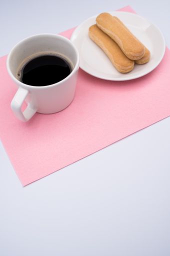 black coffee in a mug and plate with savoiardi biscuits on a wooden background with copy space