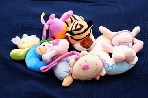A close up of a mix of colorful plush animals on a bed sheet