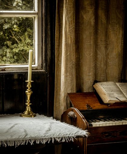 A vertical shot of a candle next to the piano inside a room