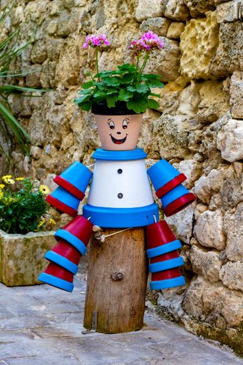A decorative figure with flower pots in a garden