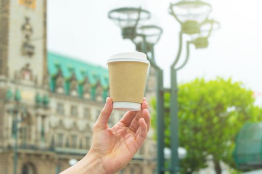 Hand holding a takeaway coffee cup in a city.	No logos or brands. For mockups.