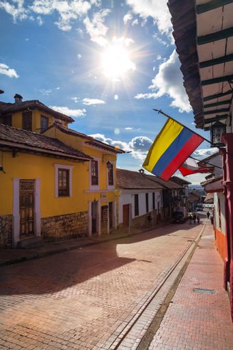 The Colombian flag flies over a cobblestone street in the Candelaria neighborhood of Bogota, Colombia