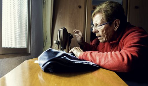 A shot of elderly female remodeling pieces of clothing using a sewing machine