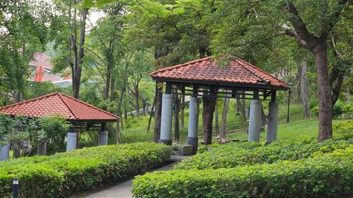 A serene park scene with traditional gazebos surrounded by lush greenery and trees.
