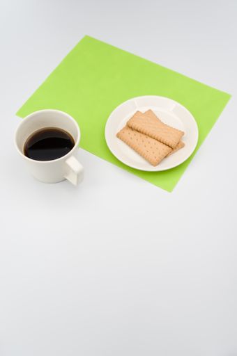 black coffee in a mug and plate with biscuits on a white background with copy space
