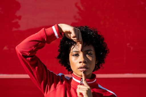 An African American female in red sport clothes sta on a red wall background
