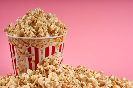 A bucket full of sweet popcorn on pink background