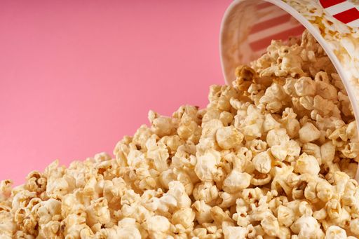 A bucket full of sweet popcorn on pink background