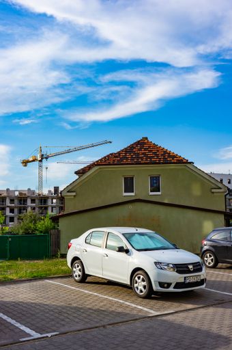 A vertical shot of cars on parking places in front of a green house in the Stare Zegrze district, Poznan, Poland