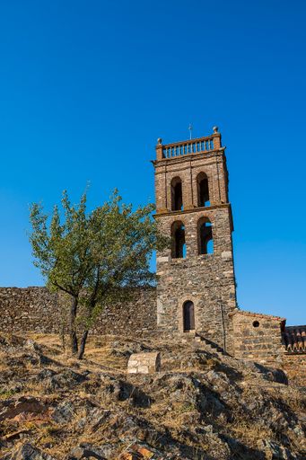 The facade of Almonaster la Real Mosque in Spai against a blue sky on a sunny day