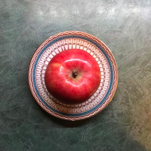 A top view of a red apple on a plate on a gray table